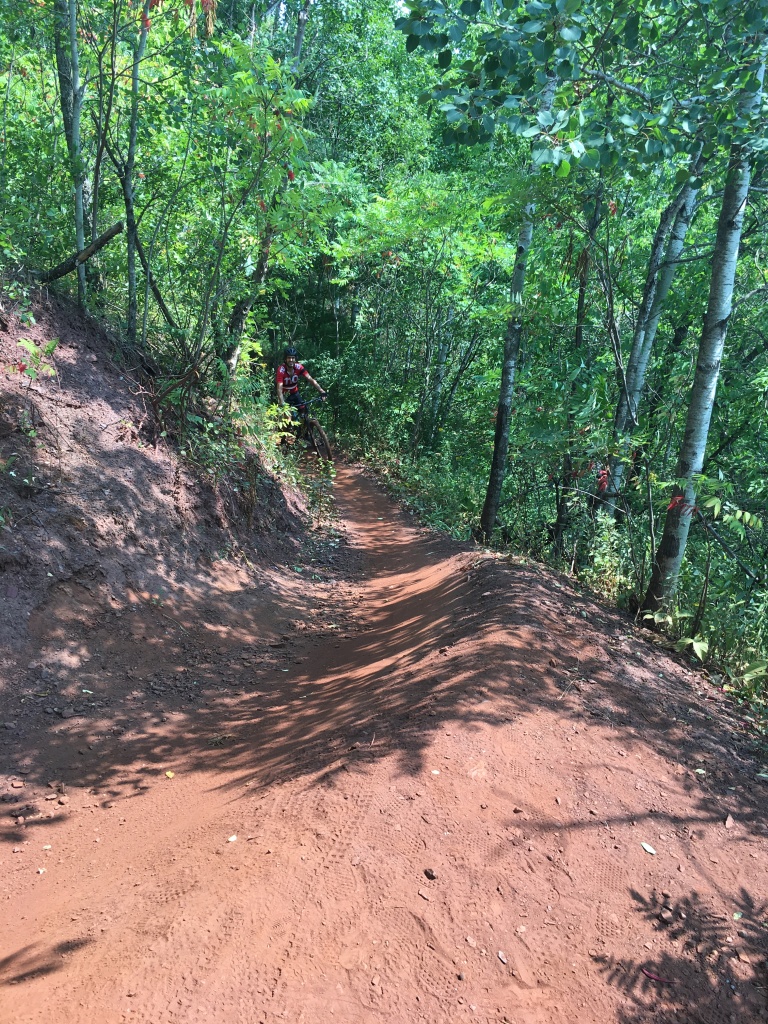 Red dirt mountain bike trail in the woods.